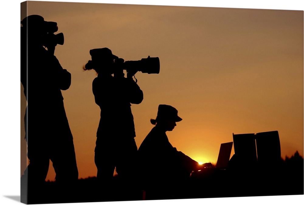 Three U.S. Air Force Visual Information professionals: a videographer (left), a still photographer (center), and a graphic...