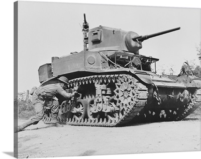 Soldier places a 29 pound TNT satchel charge on the bogey of a light tank