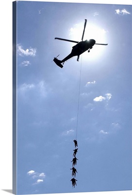 Soldiers and Airmen hang 100 feet above the ground from a UH-60 Blackhawk