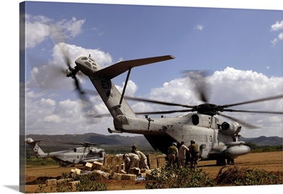 Soldiers And Sailors Help Pile Boxes Of Food And Water Off A CH-53E Helicopter