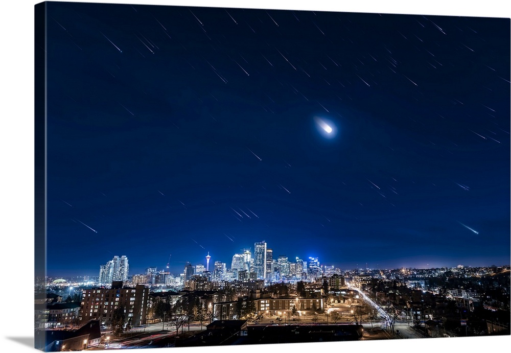 Star trails of Orion, the moon, and the stars of winter over downtown Calgary, Canada.