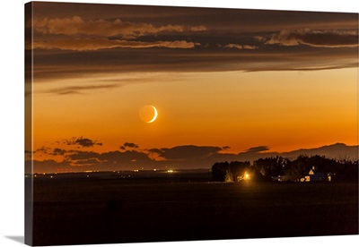 The Waxing Crescent Moon Setting Over A Nearby Farm In Alberta, Canada