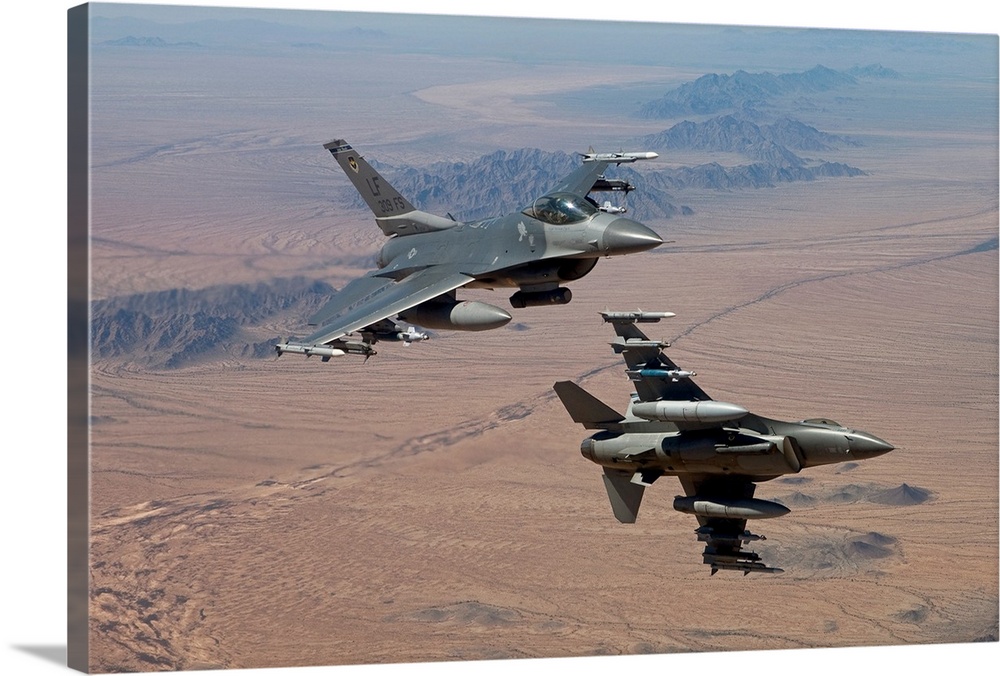 Two F-16's from the 56th Fighter Wing at Luke Air Force Base, Arizona, manuever on a training mission over the Arizona des...