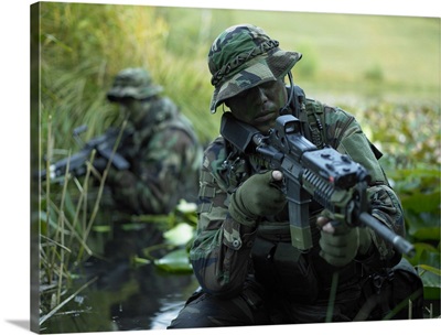 U.S. Navy SEALs cross through a stream during combat operations