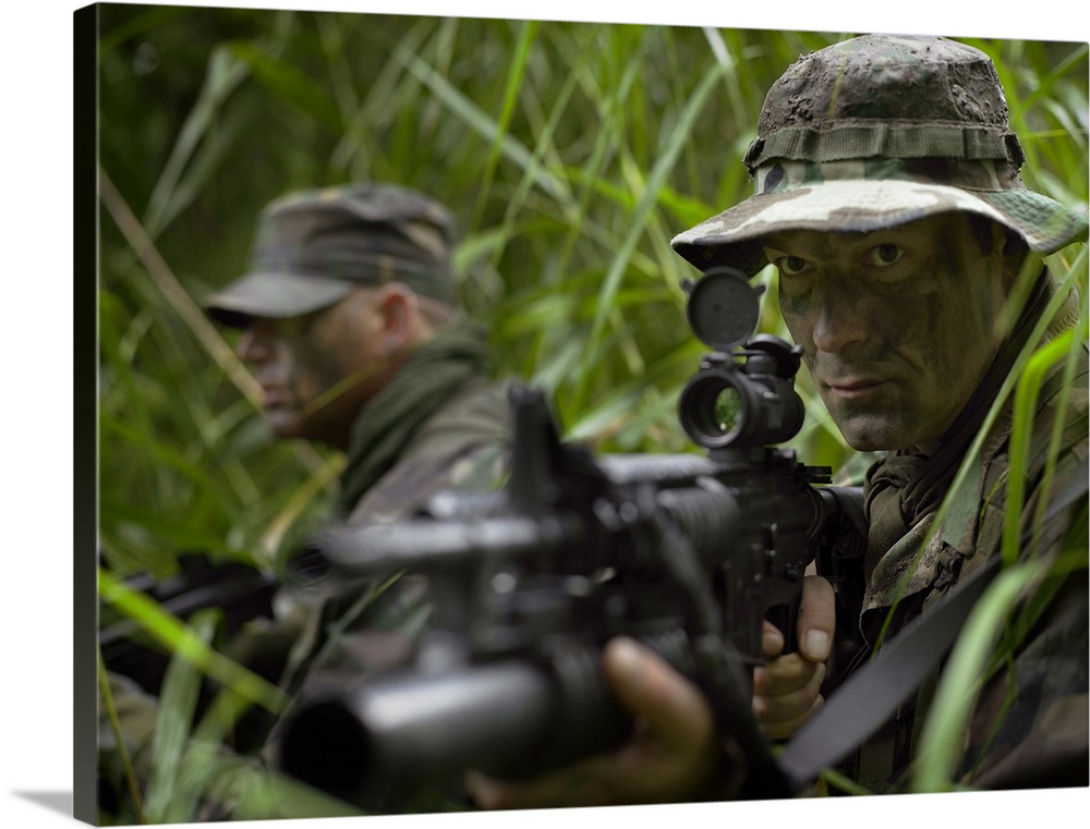 U.S. Special Forces soldiers patrol through tall grass during combat.