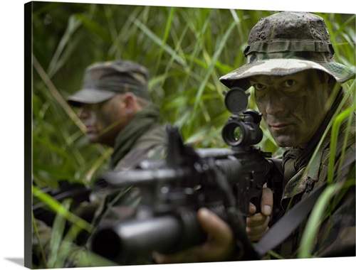 U.S. Special Forces soldiers patrol through tall grass during combat ...