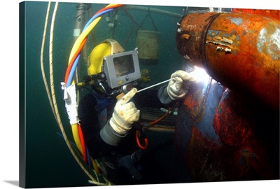 US Navy Diver welds a repair patch on the submerged bow of the USS Ogden