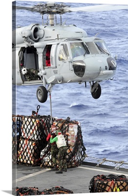 US Sailors connect a cargo pendant to an MH-60S Seahawk helicopter