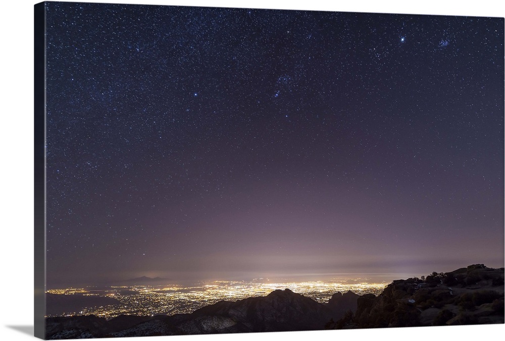 A view from midway up Mount Lemmon, looking down into Tucson, Arizona. Orion, Jupiter, and the Pleiades float above the ci...