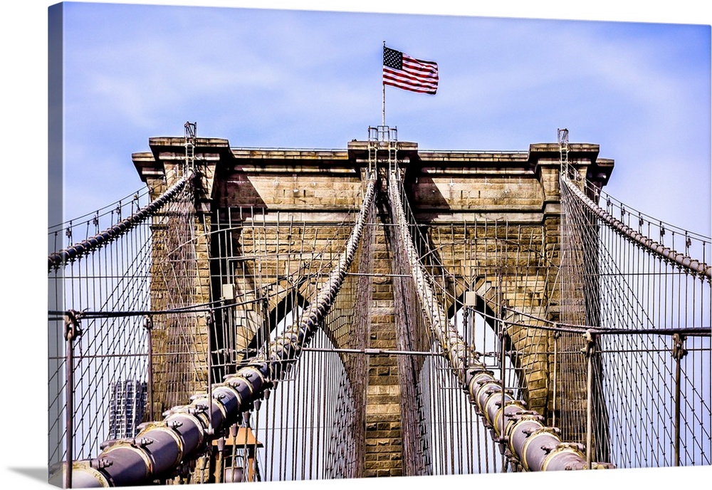An architectural photograph of the Brooklyn Bridge with the American flag on top.