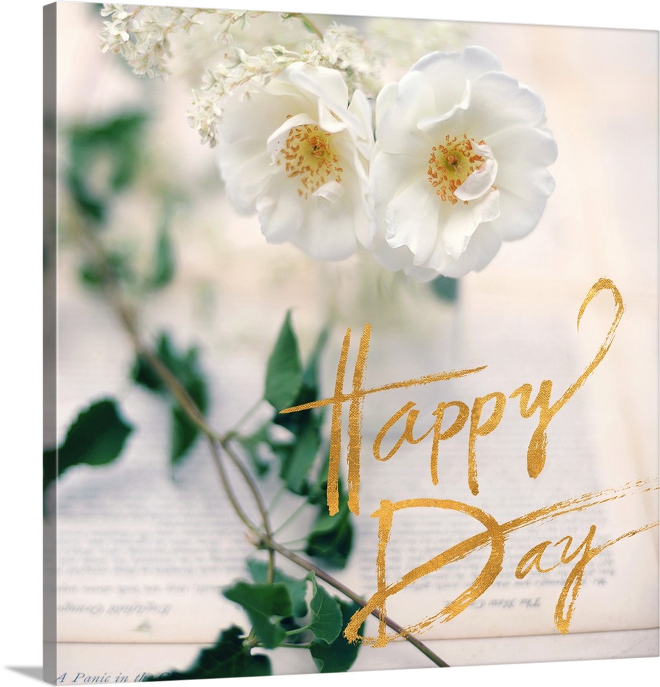 A photograph of white flowers, green leaves, and two book pages with an overlay of golden text reading "Happy Day"