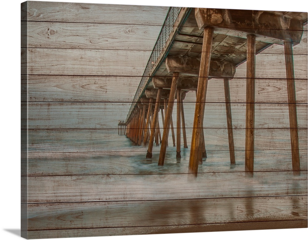 A pier stands strong as ocean water tranquilly moves underneath over faux wood planks.