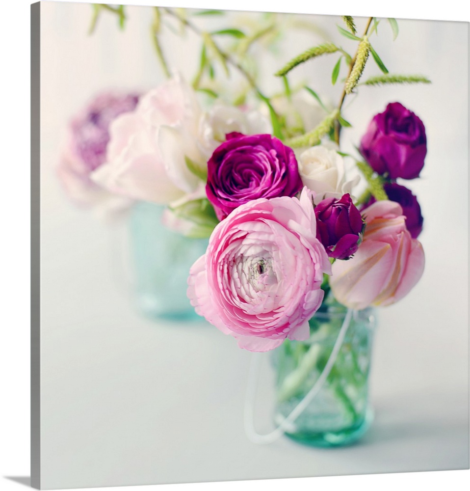 A photograph of pink, white, and purple flower arrangements in blue tinted mason jars.