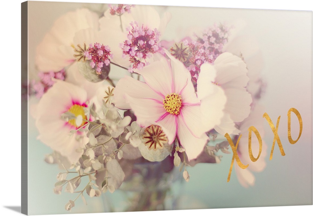 Soft, pink toned photograph of flowers arranged in a vase with "XOXO" written in gold on the side.