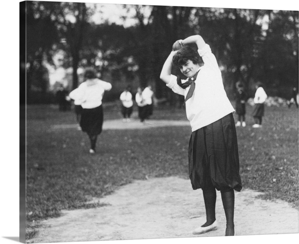 A woman on the pitcher's mound preparing to throw the ball during a softball game, c1920.
