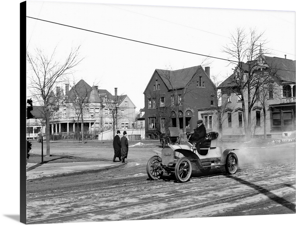 Man driving an automobile through an American town. Photograph, c1905.