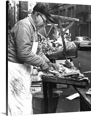 Charles Catalano cleaning fish at his pushcart on Hester Street and Mott Street, 1964