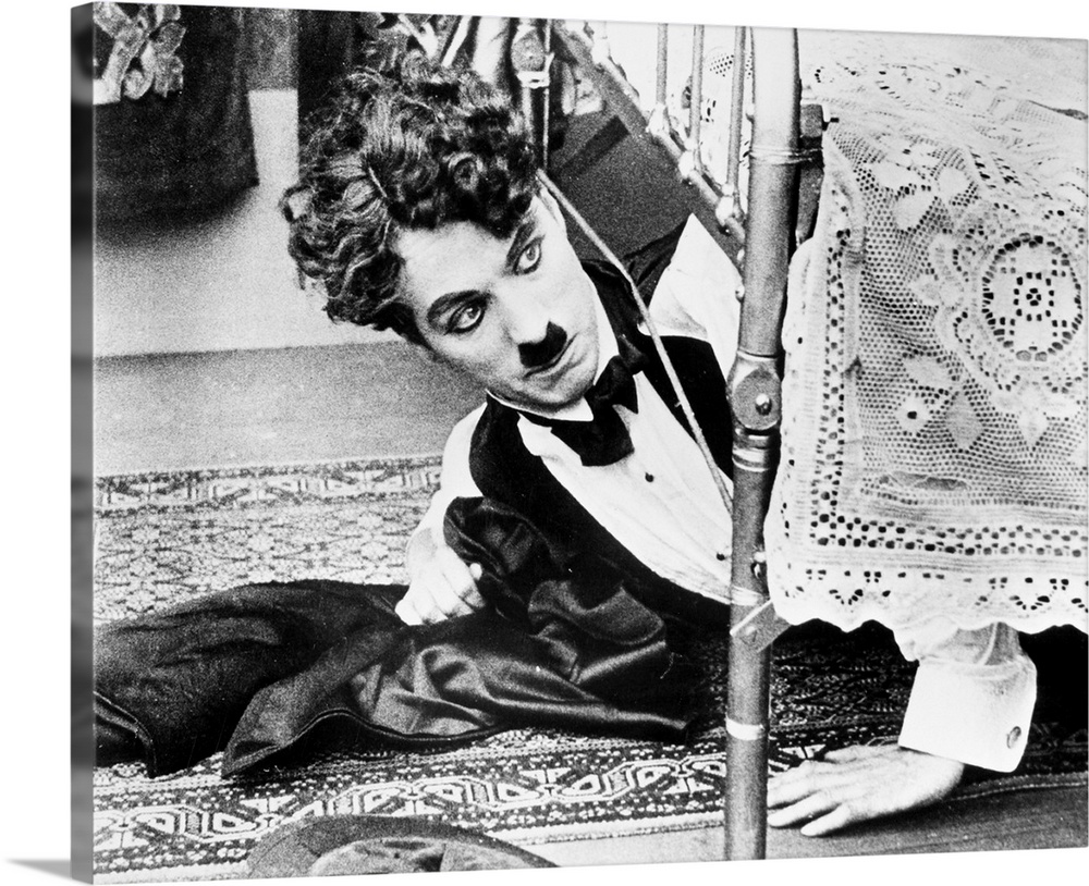 Charles Spencer Chaplin. English comedian. Getting out from under the bed in one of his silent movies from the 1920s.