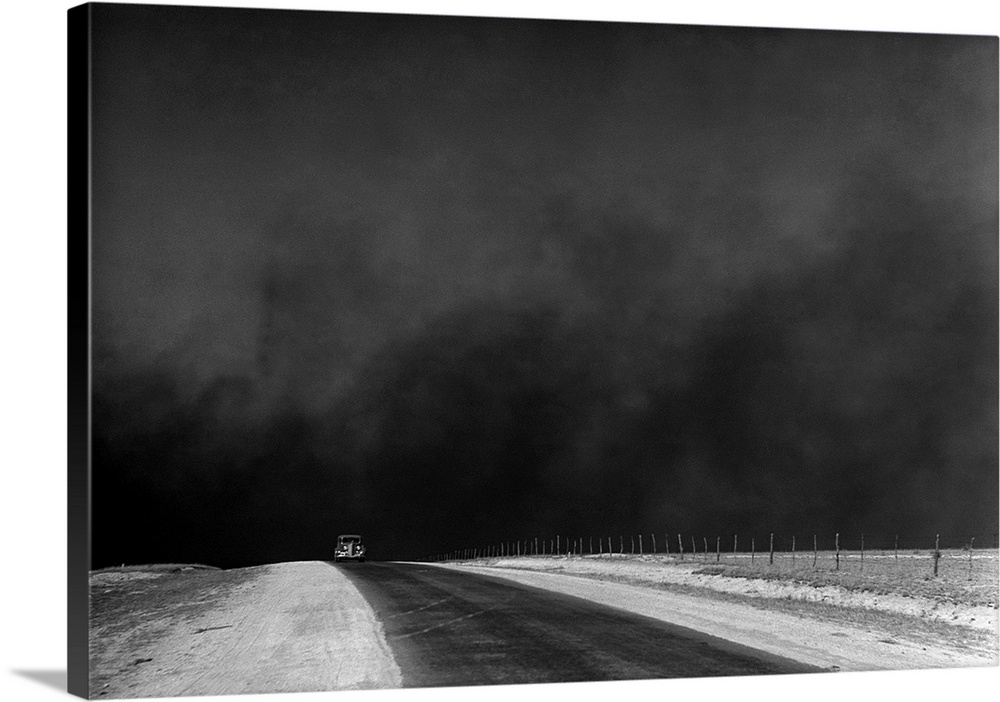 A car on a deserted road with black clouds of dust rising from the horizon, Texas Panhandle, Texas. Photograph by Arthur R...