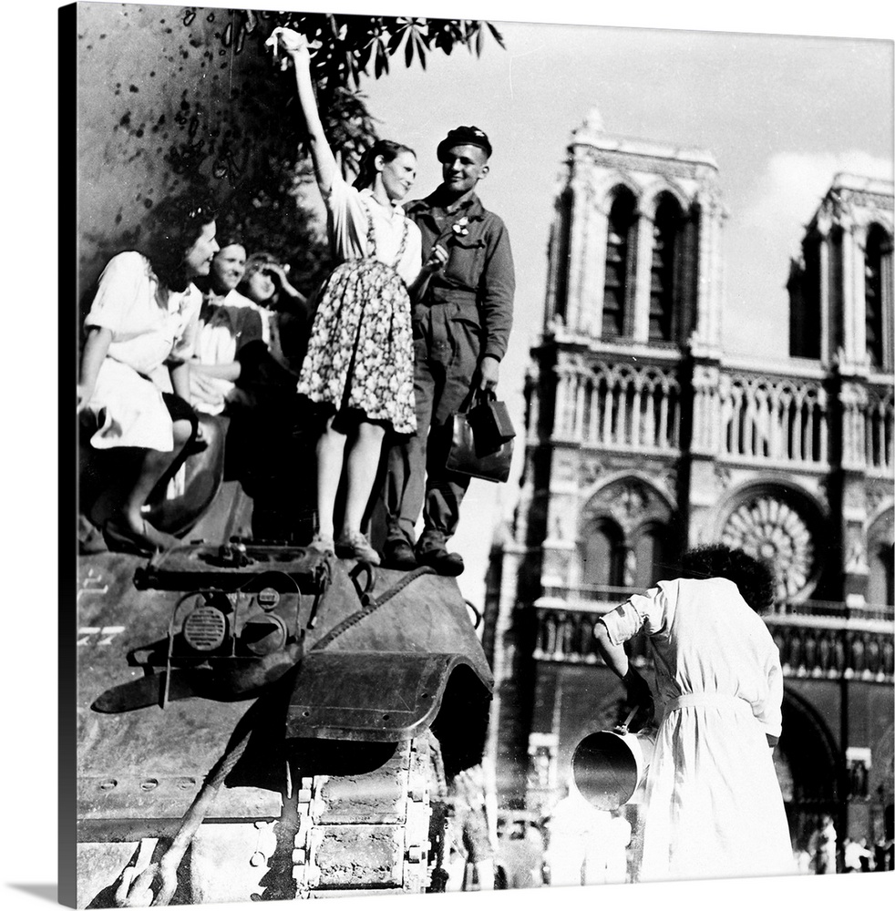 Young Parisian women join soldiers on a British tank, at Notre Dame Cathedral, after the liberation of the city by Allied ...