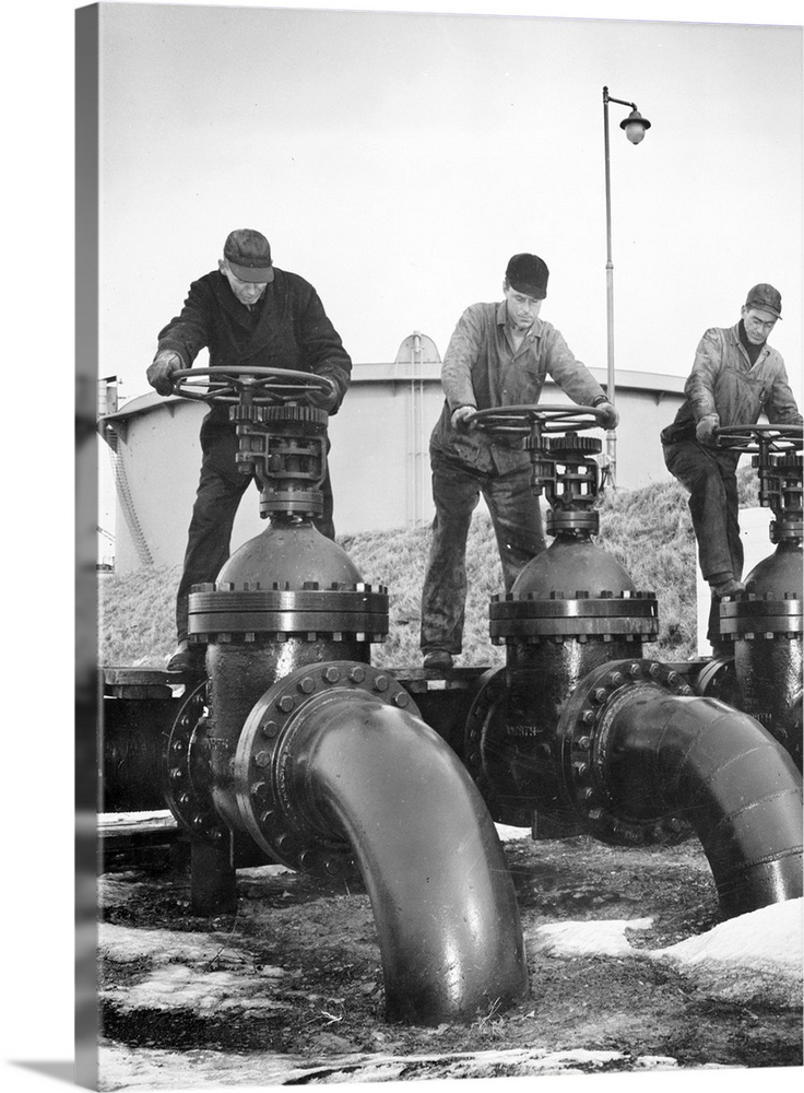 Workers at an Atlantic coast seaport in the United States regulate the flow of oil onto tankers bound for armed forces dur...