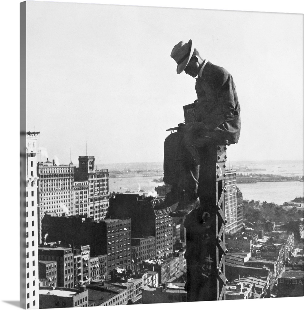 A photographer for H.C. White Co. sitting at the top of a column of a new building in New York City, 250 feet above ground...