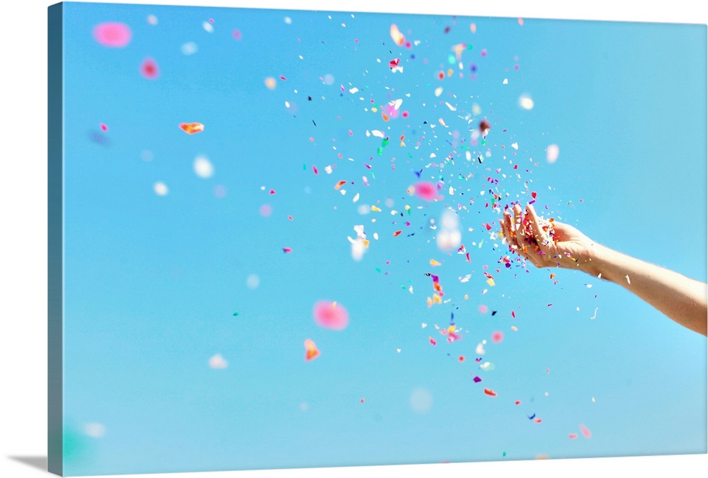 A bright, airy photograph of a hand throwing colorful confetti against a blue sky.