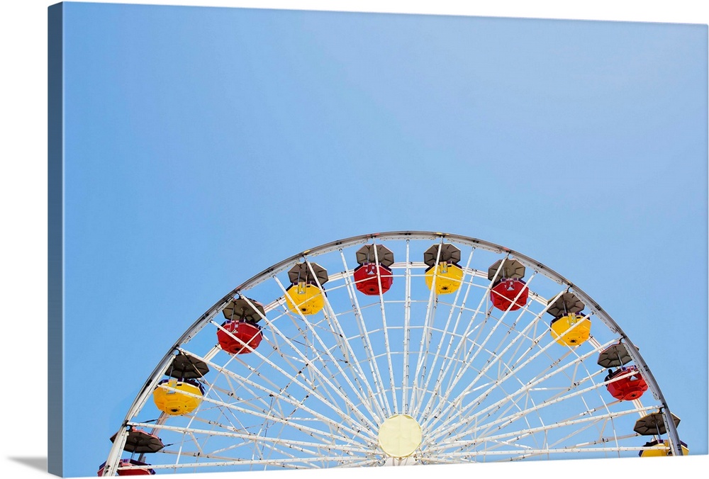 Photograph of a yellow and red Ferris Wheel against a bright, clear, blue sky.