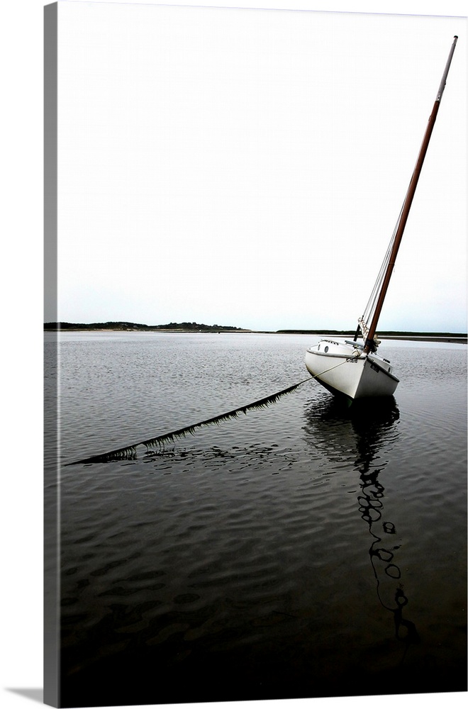 Photograph of an anchored sailboat in calm waters.