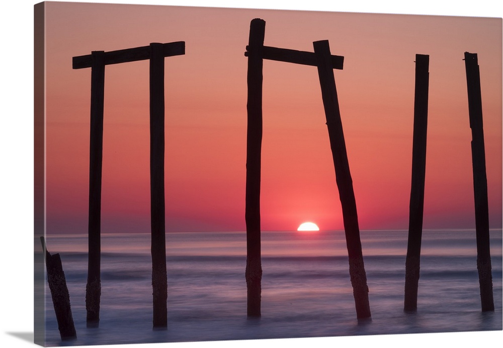 Old pilings from a fishing pier framing a sunrise on the ocean horizon, Ocean City, New Jersey.