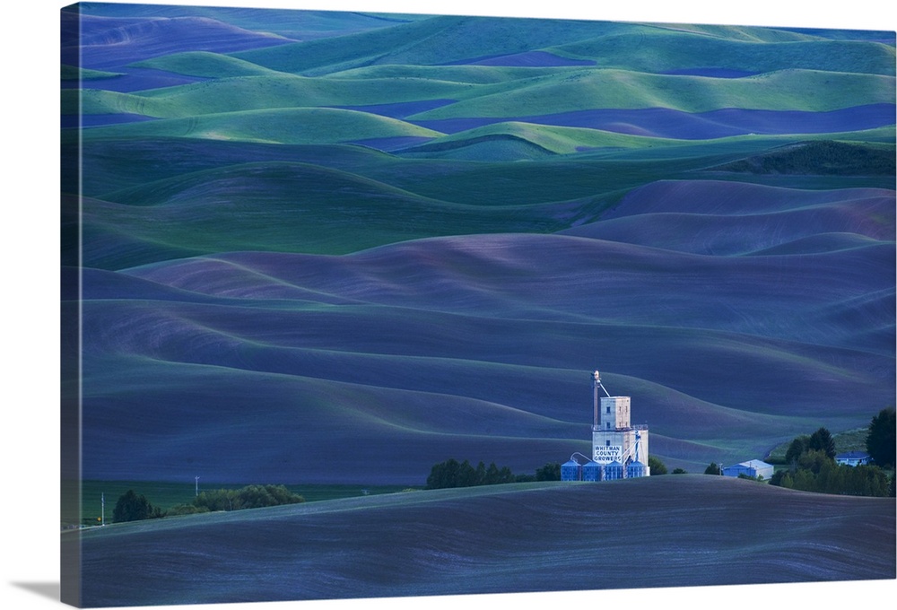 A grain elevator stands out against the deep blue hills of Palouse, Washington.