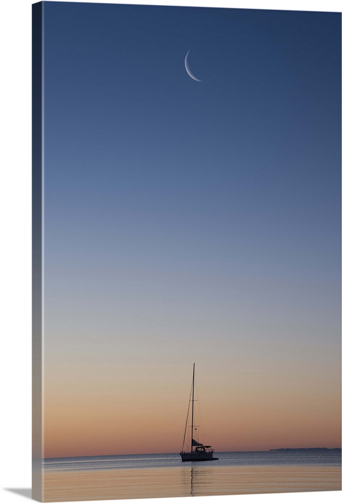 Crescent moon in the sky over a single sailboat on Lake Superior at sunset, Wisconsin.