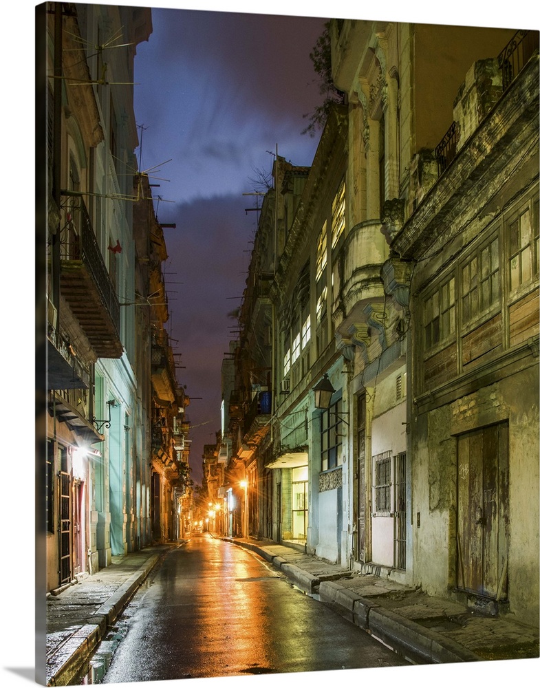 Lights from old buildings reflected on rainy streets in an alley in Havana, Cuba.
