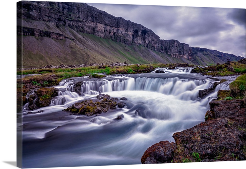 Rushing water in a freezing river under a cloudy sky in Iceland.