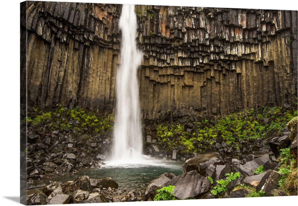Tall waterfall from a cliff with columnar basalt in Iceland.