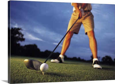 A low angle shot of a golfer preparing to tee off at a golf course