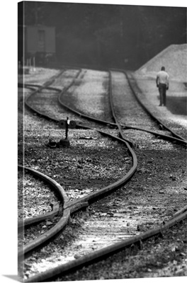A man walking beside curving railway tracks