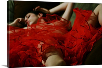 A naked woman lying under a red piece of material