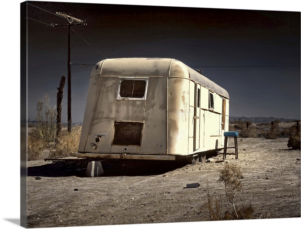 An old white caravan left to rot in the desert