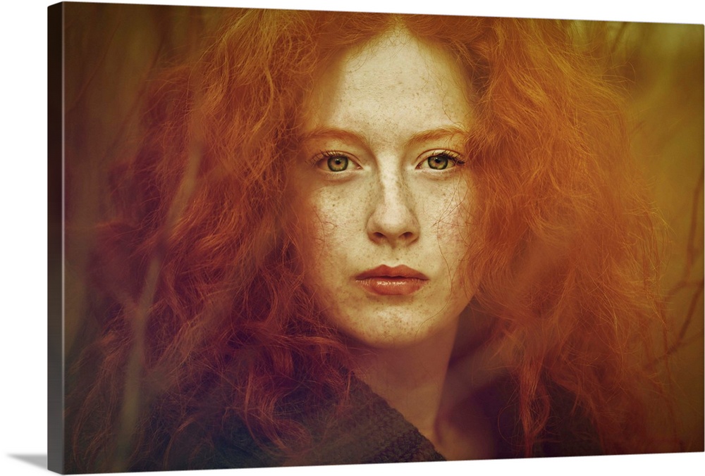 Close-up portrait of female youth withfreckles, red curly hair and piercing green eyes.