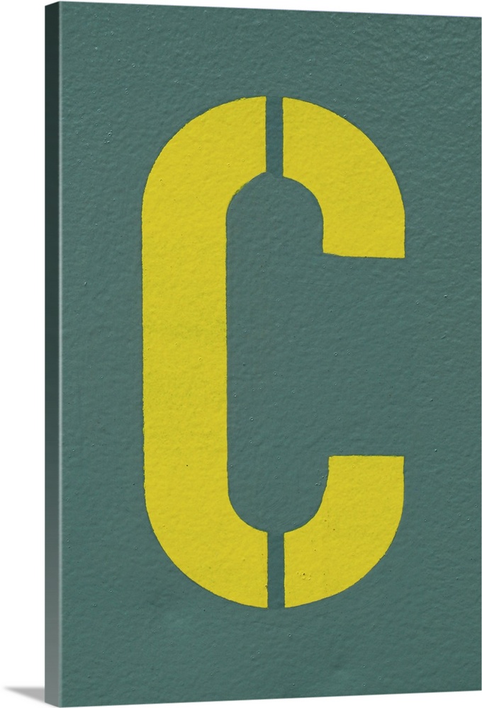 Yellow letter C sprayed on a greyish, green wall.