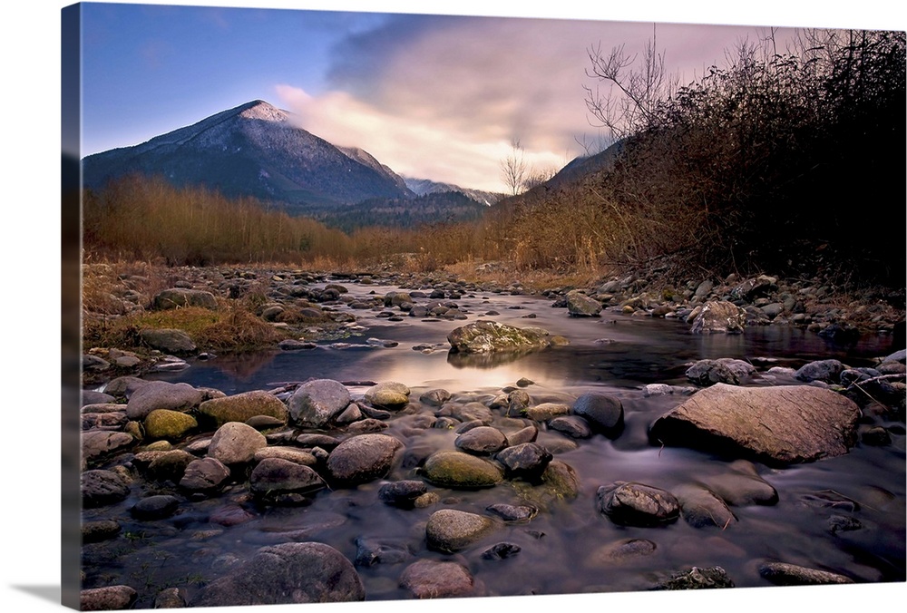 A rocky river overlooking a mountain at sunset.