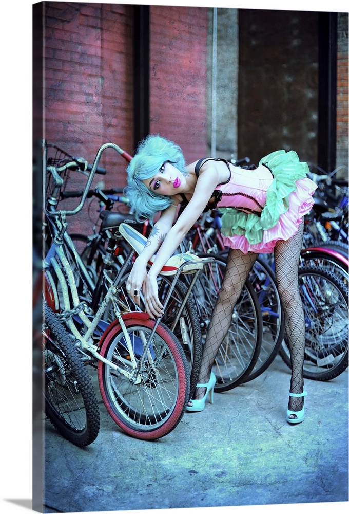 A blue-haired model poses in a tutu against a rack of bikes with a surprised expression.