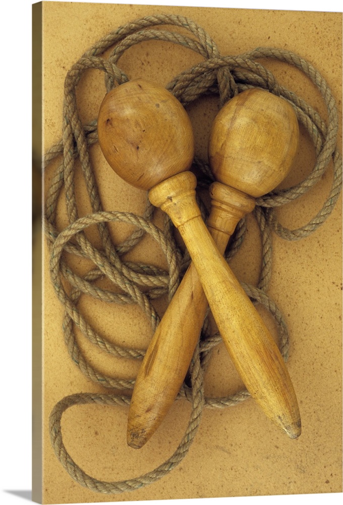 Close up of traditional skipping rope with carved and turned wooden handles lying on antique paper