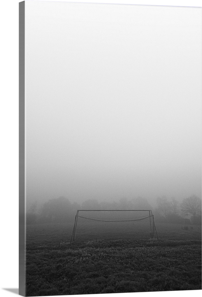 A simple football goal on an empty abandoned field on a foggy morning