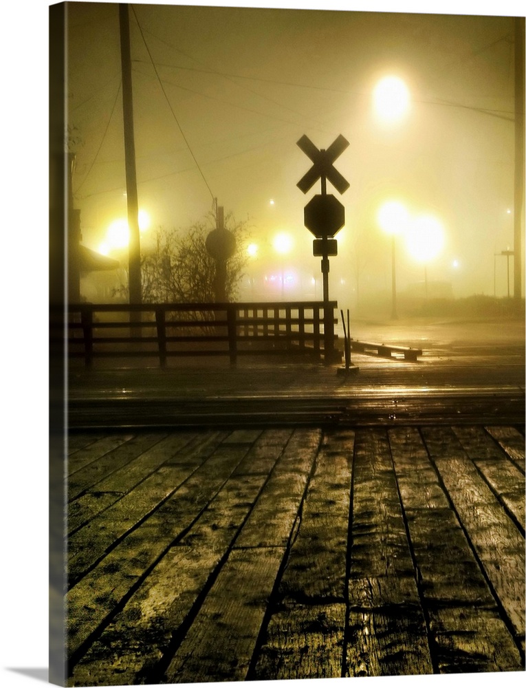 Fog at a rail crossing with street lights in the distance
