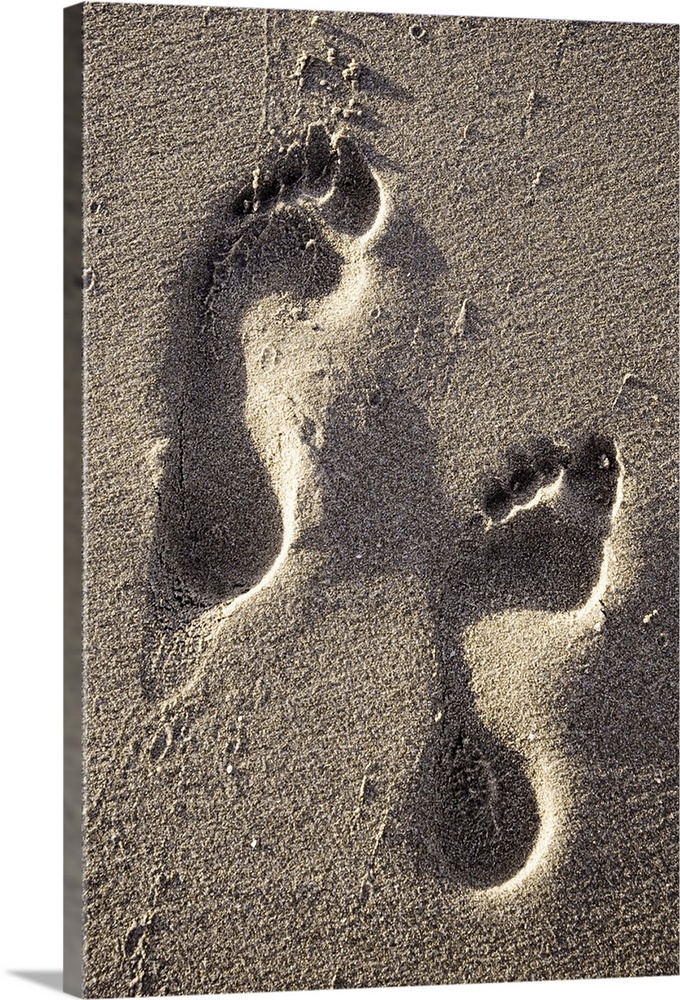 Two footprints in the sand of a beach