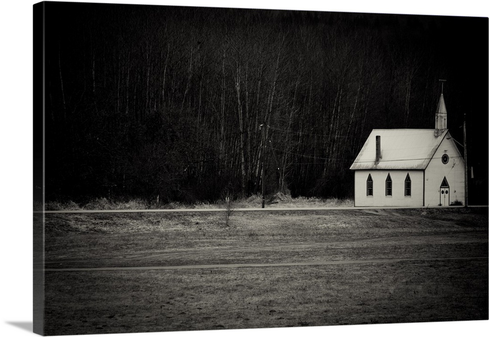 A little white church sitting in the woods looking deserted.