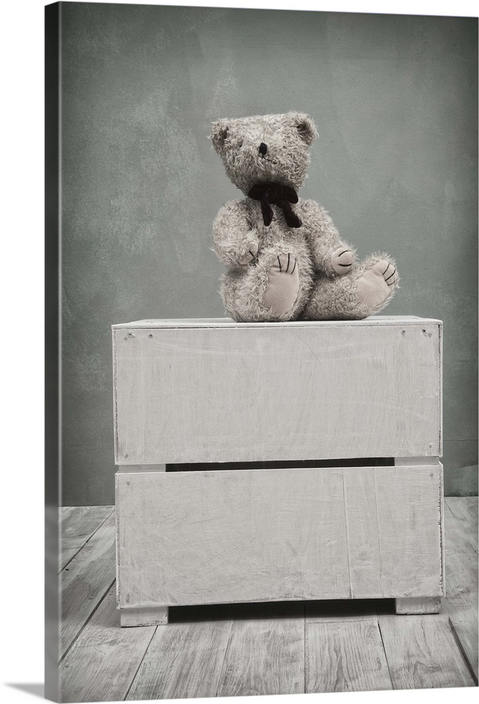 Small toy bear sat on the top of a box in a childrens playroom