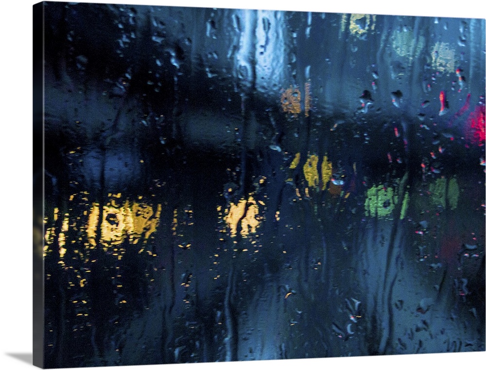 A rain strreaked window with blurred city lights.